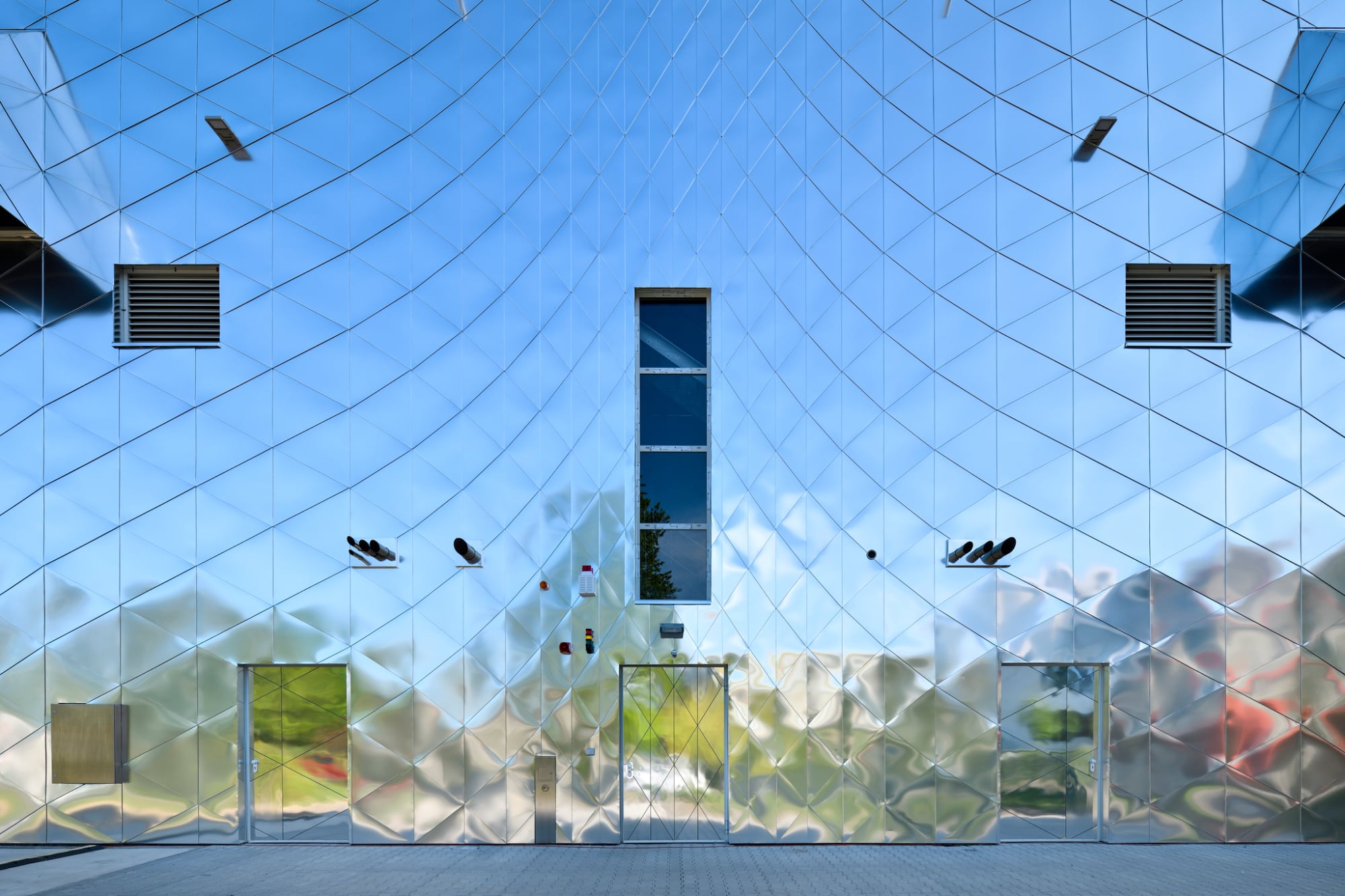 Zehn unterschiedlich dimensionierte Aluminium-Dreiecke sind so angeordnet, dass ein netzartig verzerrtes Fugenbild mit dreidimensionalem Effekt entsteht.