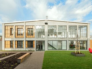 Großformatige Sprossenfenster, riesige Tore und raue Betonoberflächen – dass in dieser Halle in Landau gewohnt wird, darauf lässt sich von außen kaum schließen.