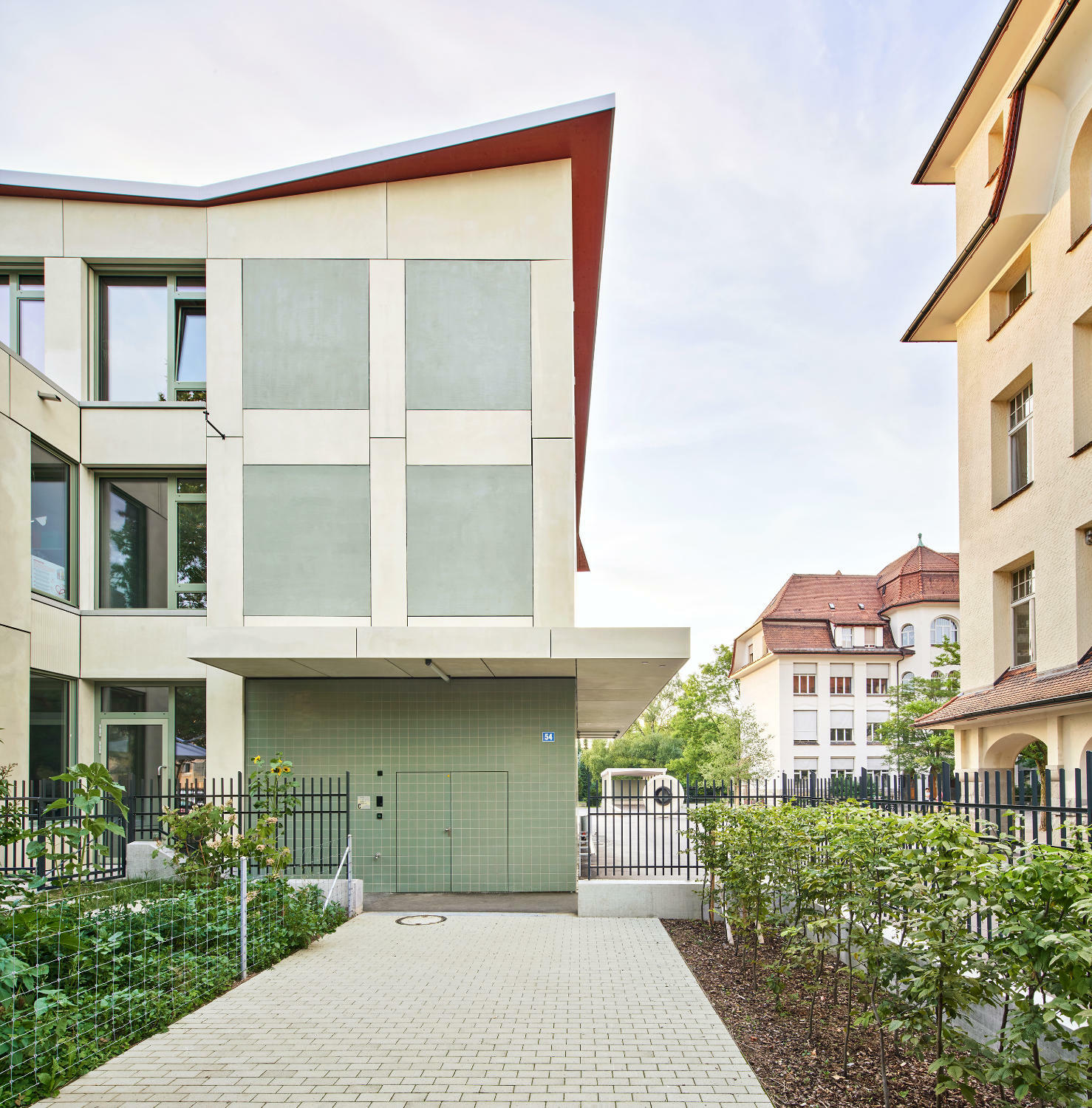 Auf allen vier Seiten kann das Gebäude betreten werden. Hier, zur Bertastrasse orientiert, ist der Eingang zum Kindergarten zu sehen, der ebenfalls in dem Neubau untergebracht wurde.