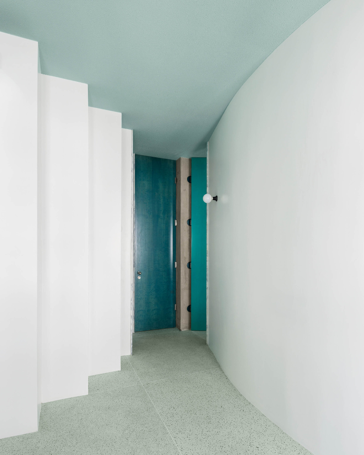 Der mit grünem Pigment versetzte Terrazzoboden bildet ein beruhigendes Gegenüber zu den eigenwilligen, vertikalen Elementen.