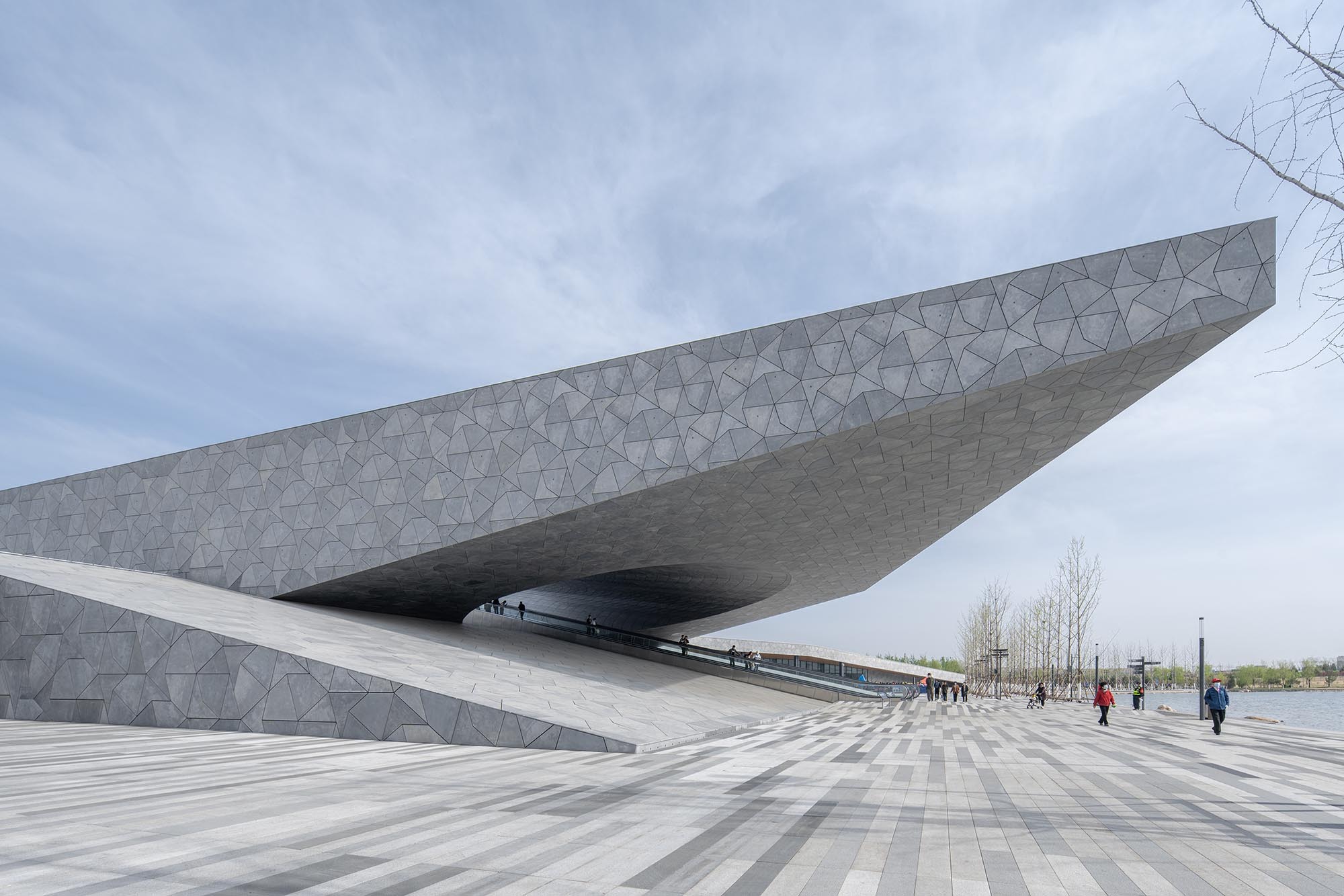 Das weit auskragende Dach ist weithin sichtbar und bildet einen architektonischen Kontrapunkt zu den holzdominierten Gewächshäusern und dem Teehaus. 