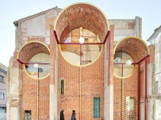 Für die durch Abriss sichtbar gewordene Brandwand mit den Spuren der vorherigen Wohnungen entwarf das ortsansässige Architekturbüro Unparalld'Arquitectes eine Gewölbestruktur aus roten Hohlziegeln.