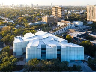 Auf dem Campus des Museum of Fine Arts in Houston haben Steven Holl Architects einen Erweiterungsbau realisiert. Der Neubau hat seitliche Einschnitte und eine geschwungene Dachlandschaft.