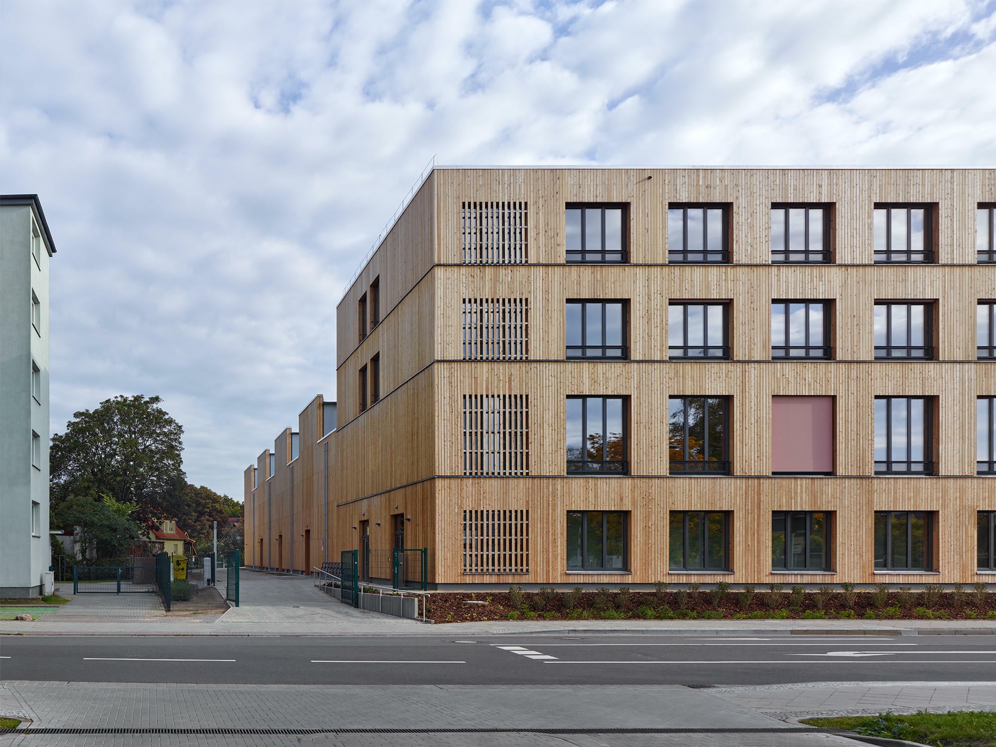 Dank der umfassenden Holzfassade erscheinen die Gebäudeteile als Ensemble.