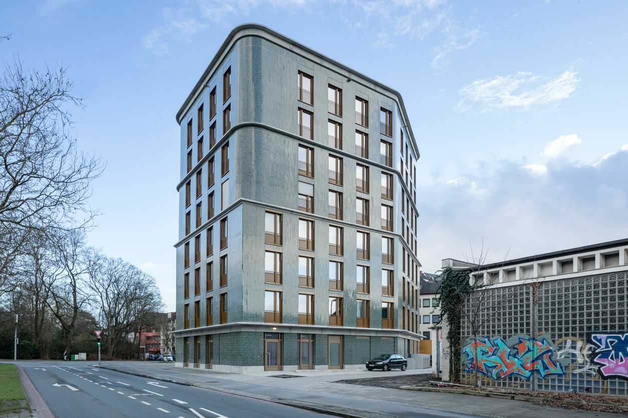 Rücksprünge ab dem vierten und sechsten Stockwerk, unterschiedlich profilierte Gesimse und der Wandel von eckigen zu abgerundeten Ecken ab dem fünften Obergeschoss zonieren die Fassade.