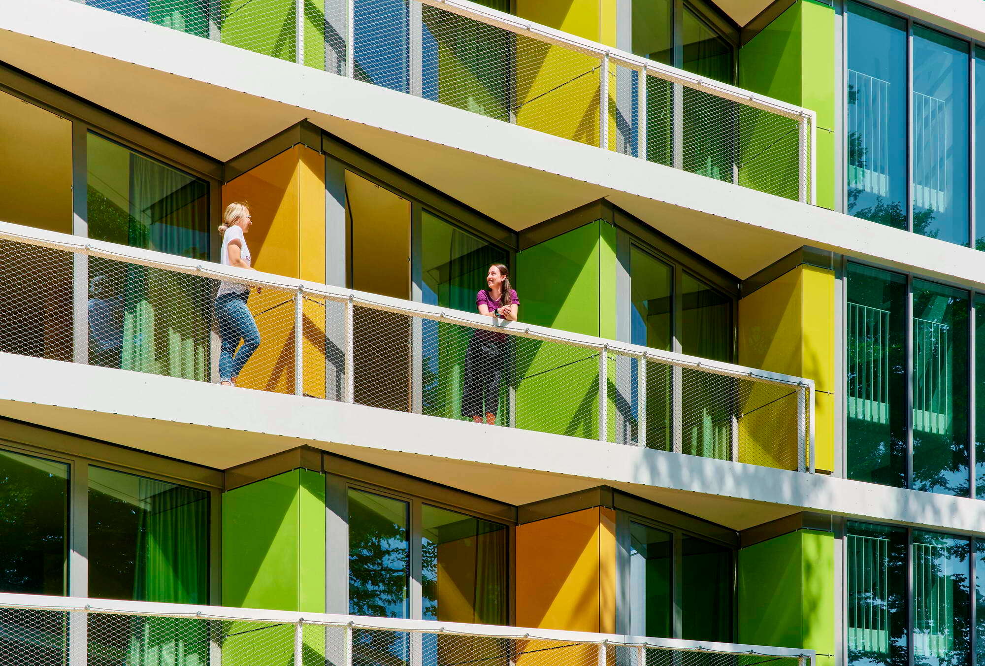 Die kräftig orange-rote und grüne Farbgebung der Sichtschutzwände der Balkone ist von der jahreszeitlichen Laubfärbung der umliegenden Bäume inspiriert.