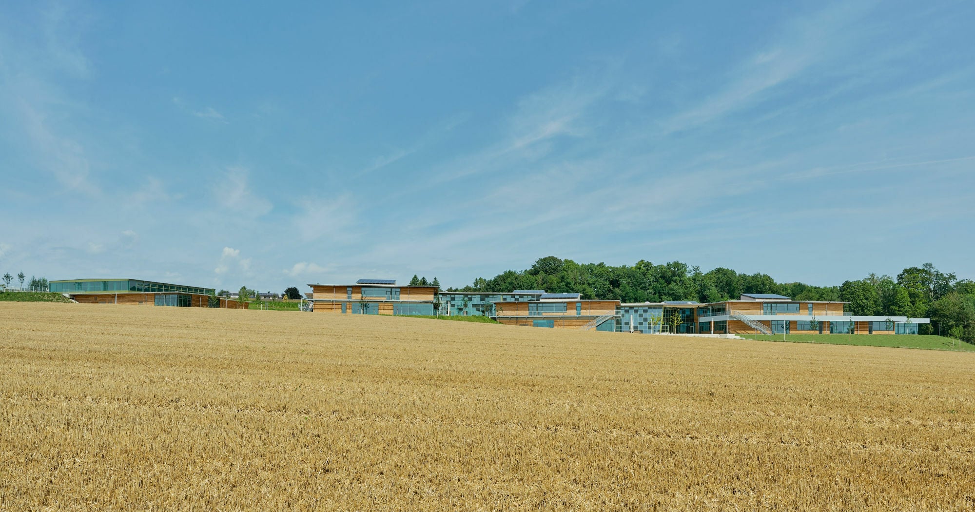 Der in der Höhe gestaffelte Gebäudekomplex nach Plänen einer Arbeitsgemeinschaft von Behnisch Architekten mit Leinhäupl + Neuber erstreckt sich auf ehemals landwirtschaftlich genutztem Gelände.