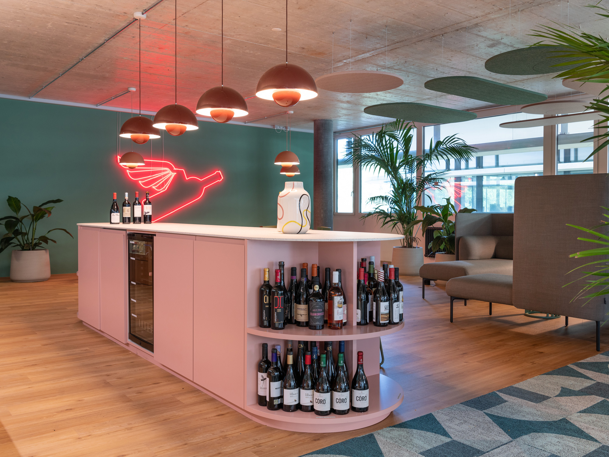 Das Büro ist in verschiedene Zonen gegliedert, was sich auch an der Bodengestaltung zeigt. Im Barbereich ist der Boden neutral gehalten, während die (Einbau-)Möbel farbenfroh daherkommen.