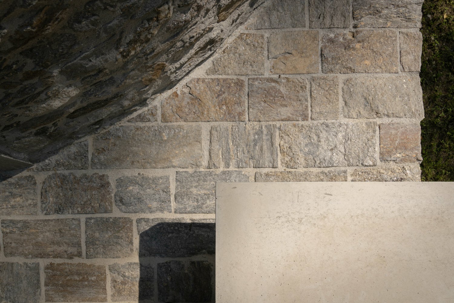 Der Vorplatz besteht aus Natursteinquadern, die Bank aus Sichtbeton.