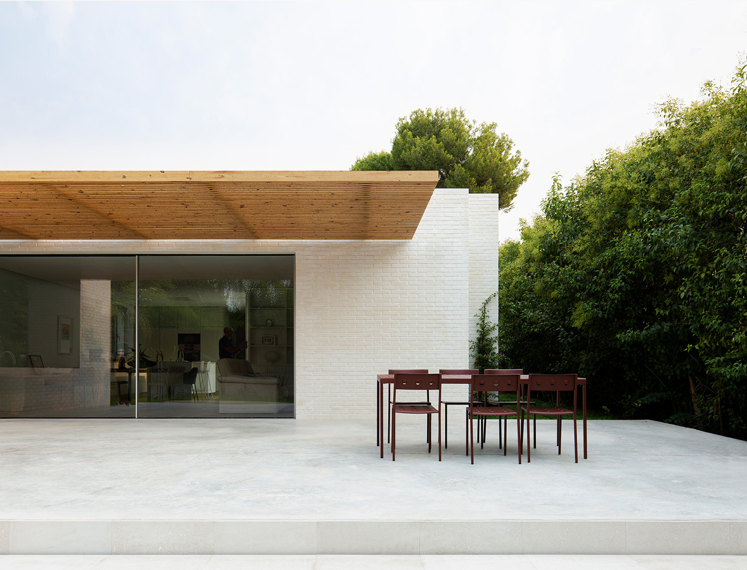 Auf der Rückseite des Hauses befindet sich eine großzügige Terrasse mit Südausrichtung, die eine Pergola aus Holzlamellen vor der Sonne schützt.