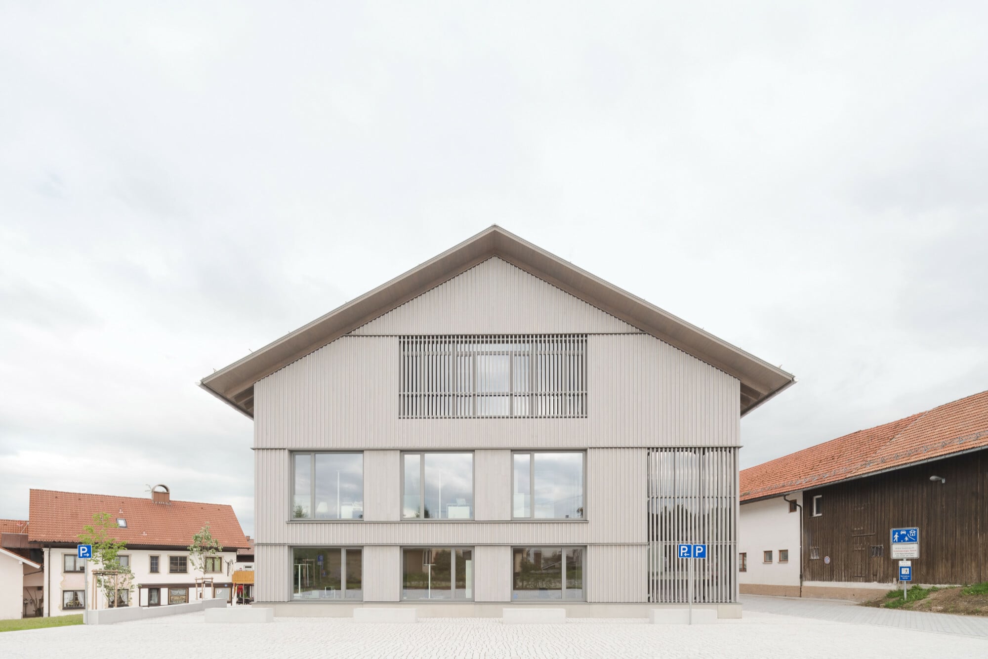 Westansicht: Oberhalb des Betonsockels ist das Gebäude mit Holz bekleidet.