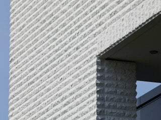 Die bruchrauen Quarzverblendern in drei unterschiedlichen Grautönen verleihen der Fassade des Wohnhauses eine lebhafte Struktur.