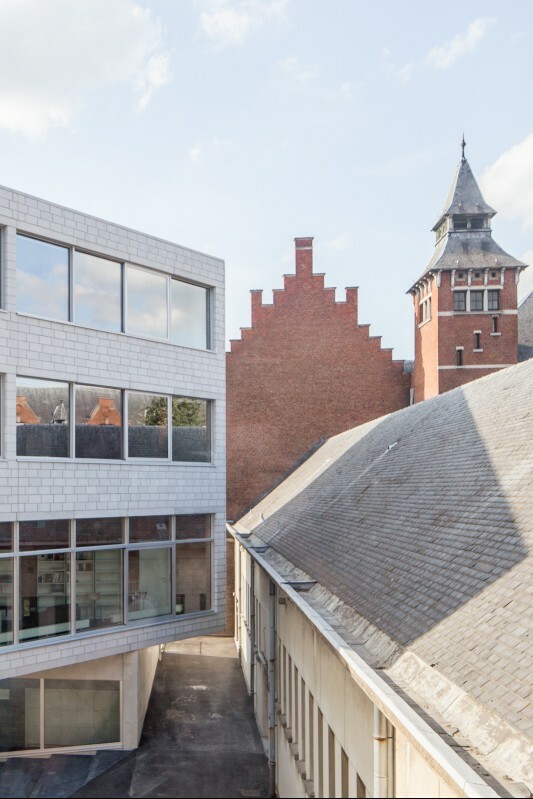 Die Sichtbetonfassade im Erdgeschoss und die Mauerwerksfassade aus weißen, unverputzten Betonsteinen der Obergeschosse haben einen rohen Charakter, der sich deutlich vom Bestand absetzt. 
