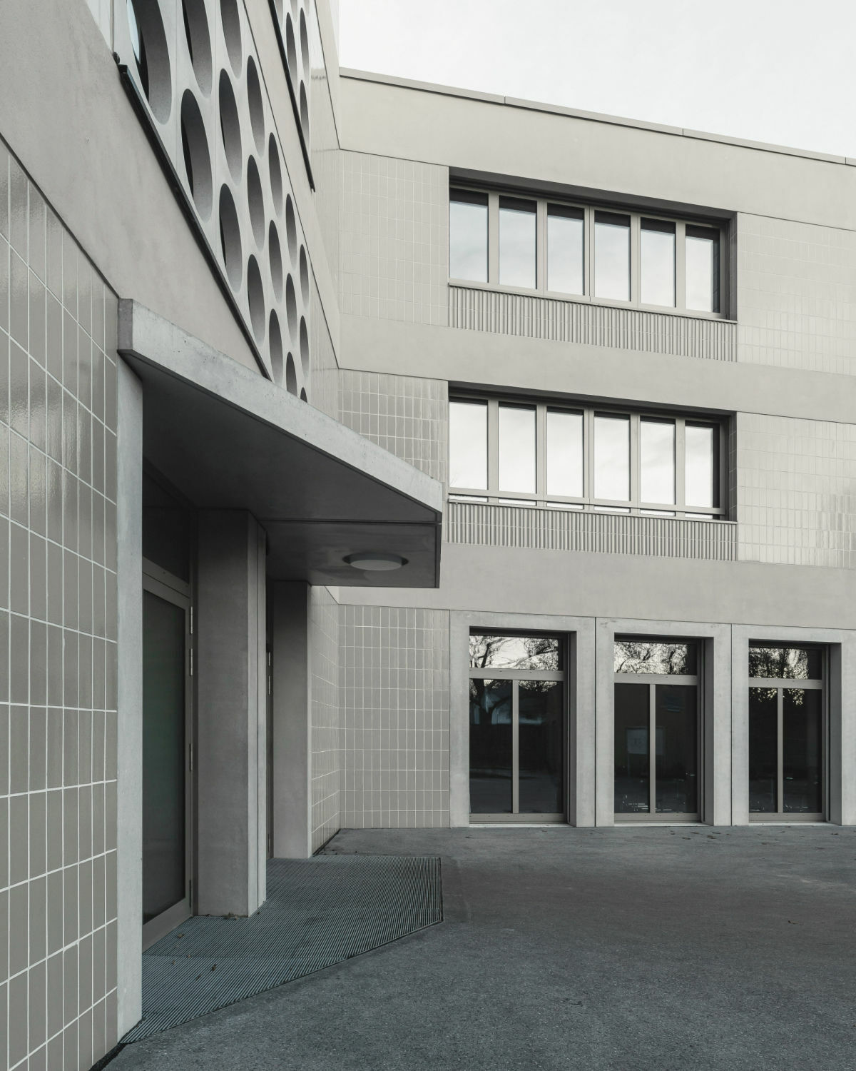 In Sichtbeton sind die Rahmenelemente der Eingänge und Erdgeschossfenster gehalten.