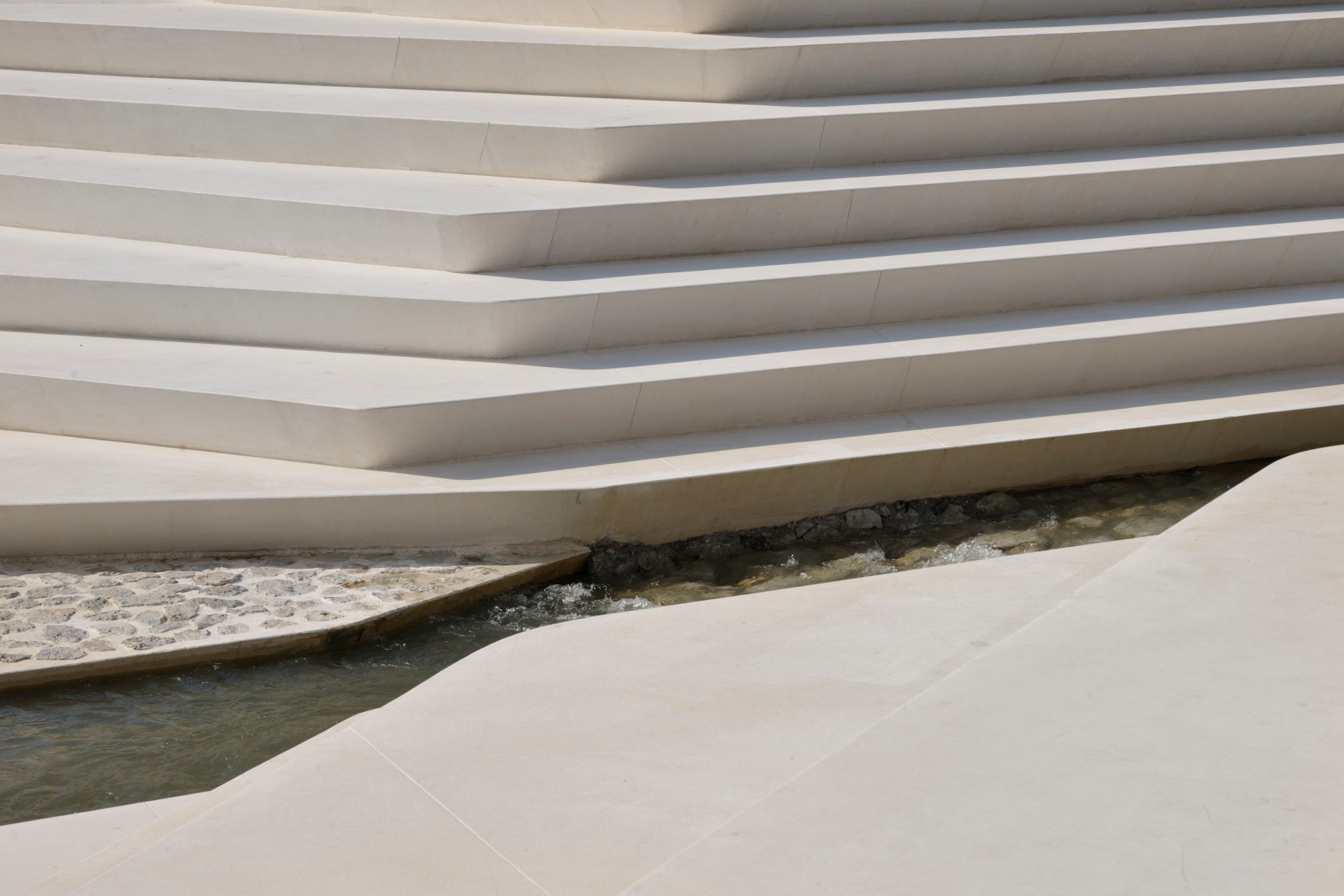 Die Stufen der eisschollenartigen Formation des Amphitheaters sind aus glattem, sandfarbenem Sichtbeton hergestellt