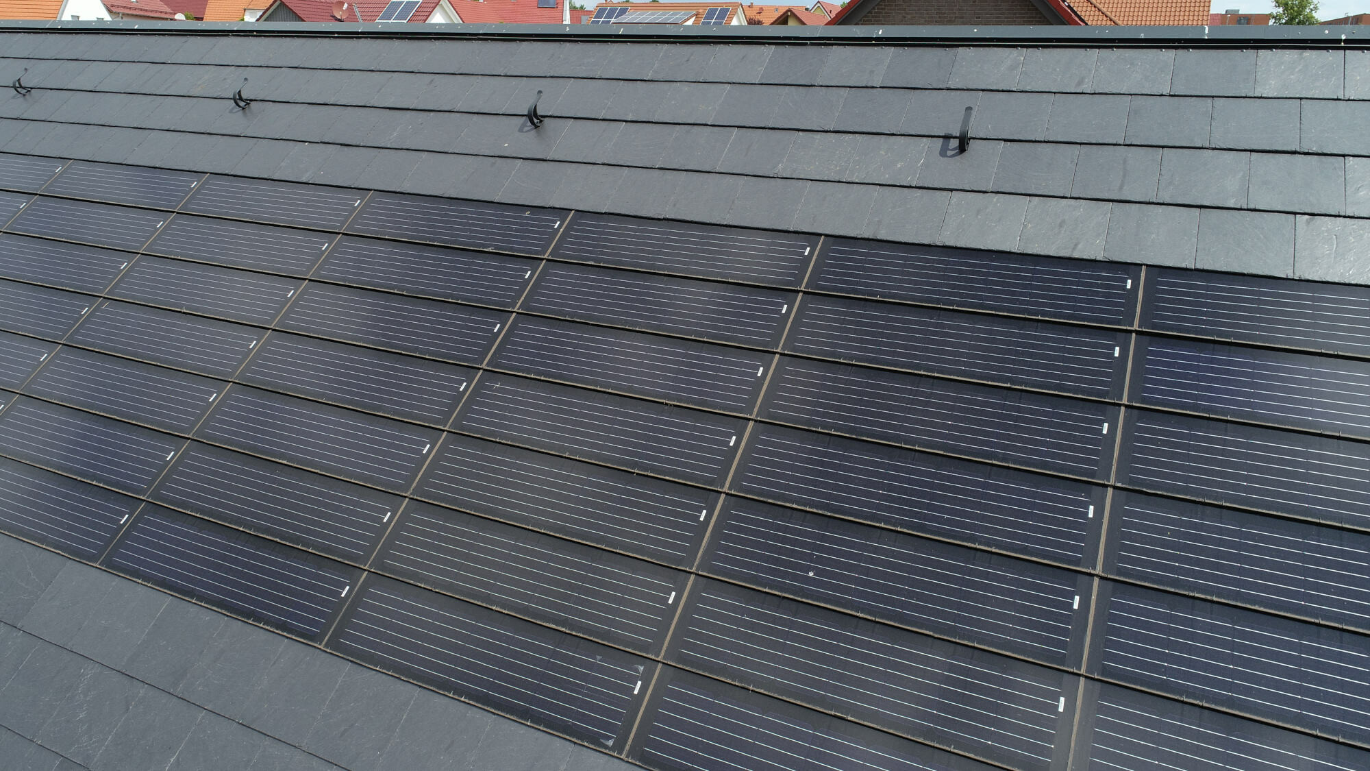 Möglich ist eine Integration von Solarpaneelen, die sich dank ihrer Maße und einer leicht schimmernden Oberfläche gut in das Raster der Schieferdeckung einfügen.