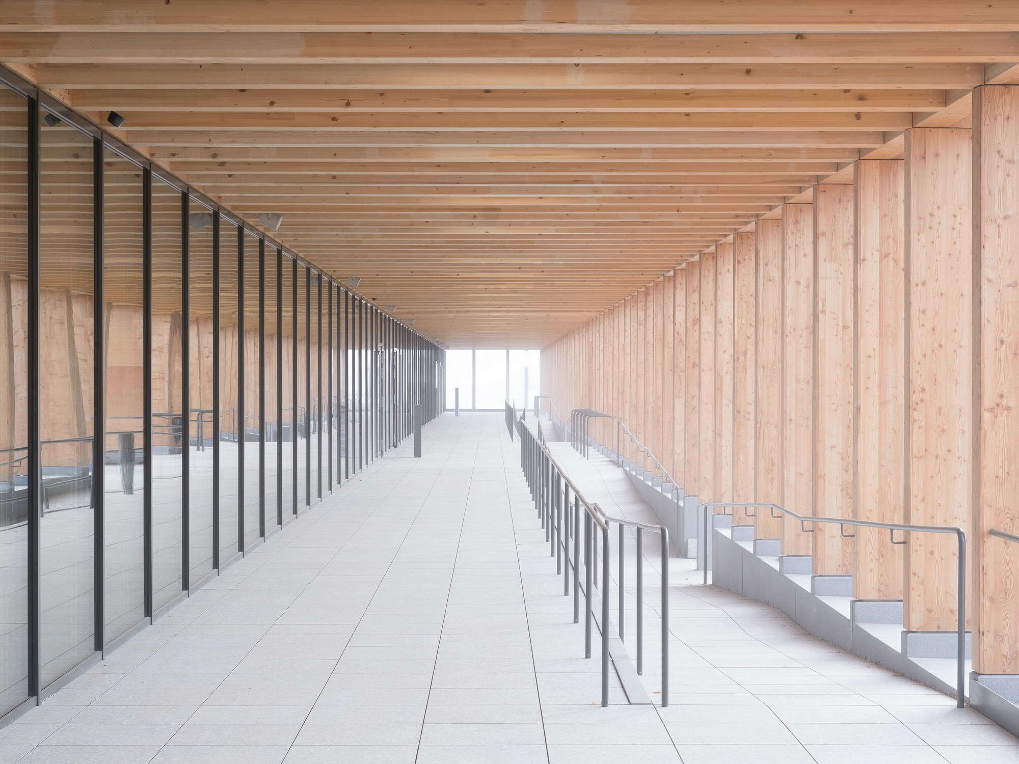 Eine Art Kolonnadengang aus Holzstützen dient als niederschwelliges Entrée in das helle und einladende Schulhaus.