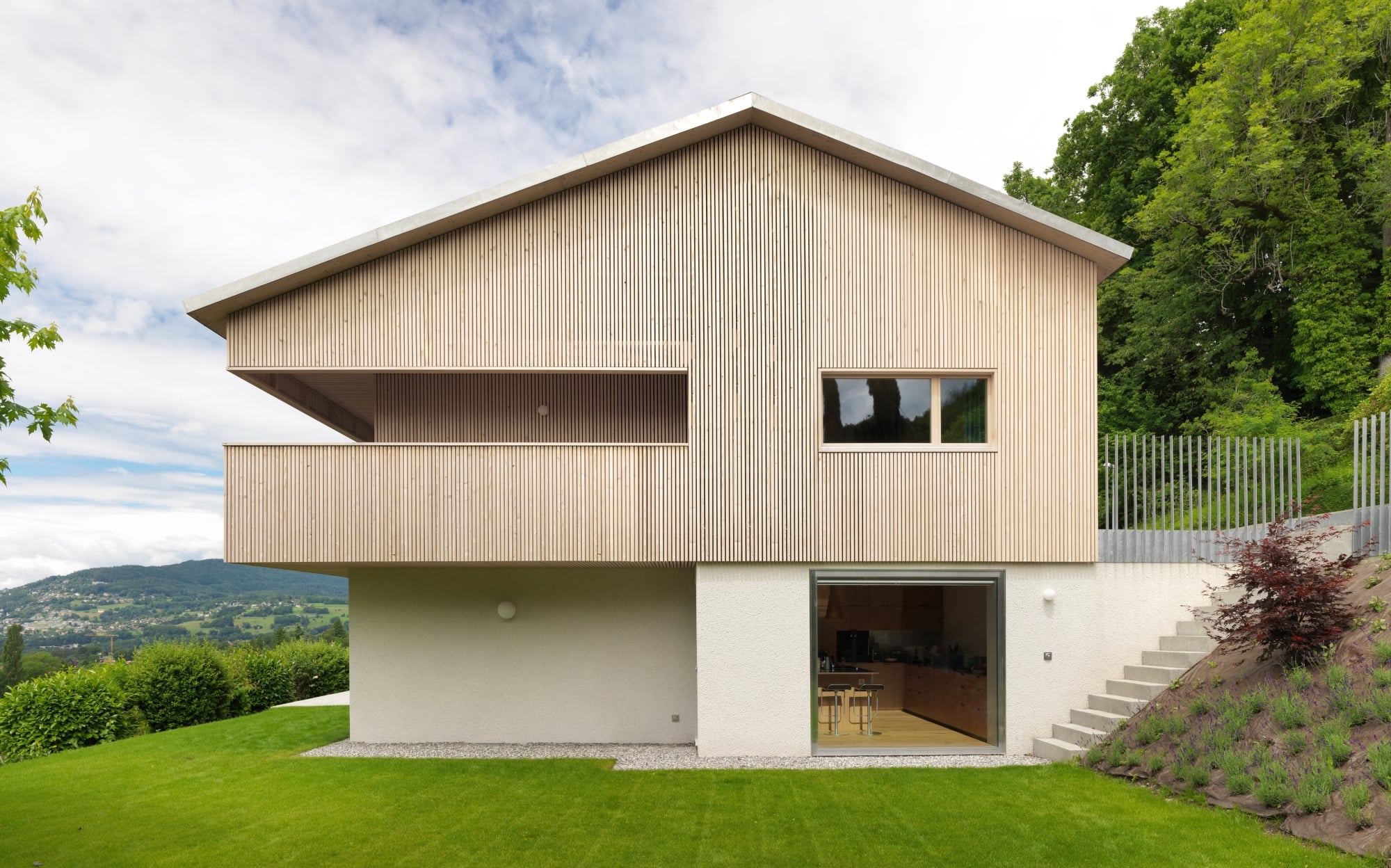 Während die Grundform des zweigeschossigen Gebäudes am Genfersee nahezu unverändert blieb, erhielt das Volumen bei der umfassenden Renovierung durch Graber & Petter Architectes eine neue Hülle aus vertikalen Holzlamellen.