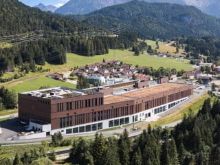 Das Produktionsgebäude nach Plänen von ATP Architekten und Ingenieure liegt inmitten der üppig bewaldeten Bergwelt von Tirol und nutzt zur Beheizung, Kühlung und Belüftung der Innenräume vor Ort gewonnene Energie.