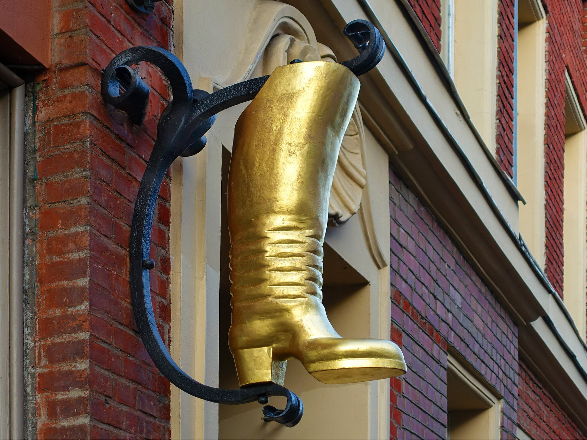 Besonders in Altstädten und historisch rekonstruierten Stadtvierteln hängen sind solche Schilder neben oder über den Eingangstüren und Schaufenstern von Geschäften, Werkstätten, Gasthäusern und Postfilialen zu finden. Im Bild: Ausleger mit einem goldenen Stiefel als Symbol für eine Schuhmacherwerkstatt
