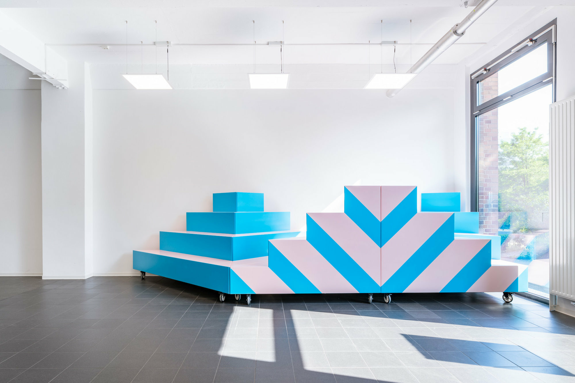 Die pyramidenartigen Elemente auf Rollen können flexibel im Raum positioniert werden.