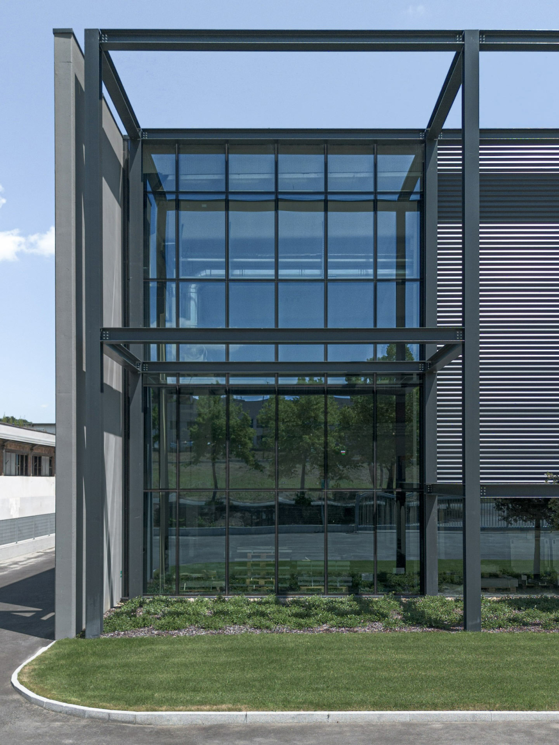 An der Gebäudeecke setzt ein gebäudehohes Fensterfeld mit einer anthrazit lackierten Pfosten-Riegel-Konstruktion einen Kontrapunkt zu den farbigen Lamellen.