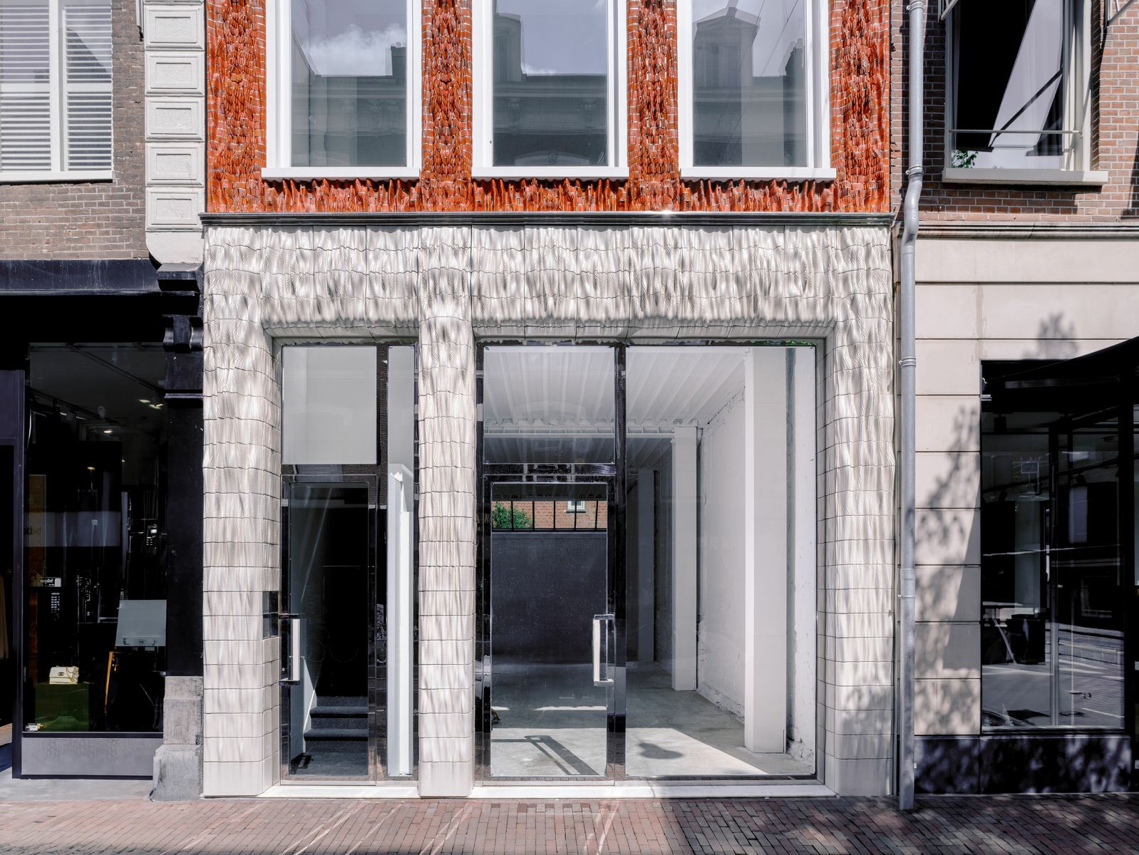 Die Fassade bildet in ihrer Gesamtheit einen textilen Faltenwurf nach, der zwischen Erd- und erstem Obergeschoss besonders plastisch ist.