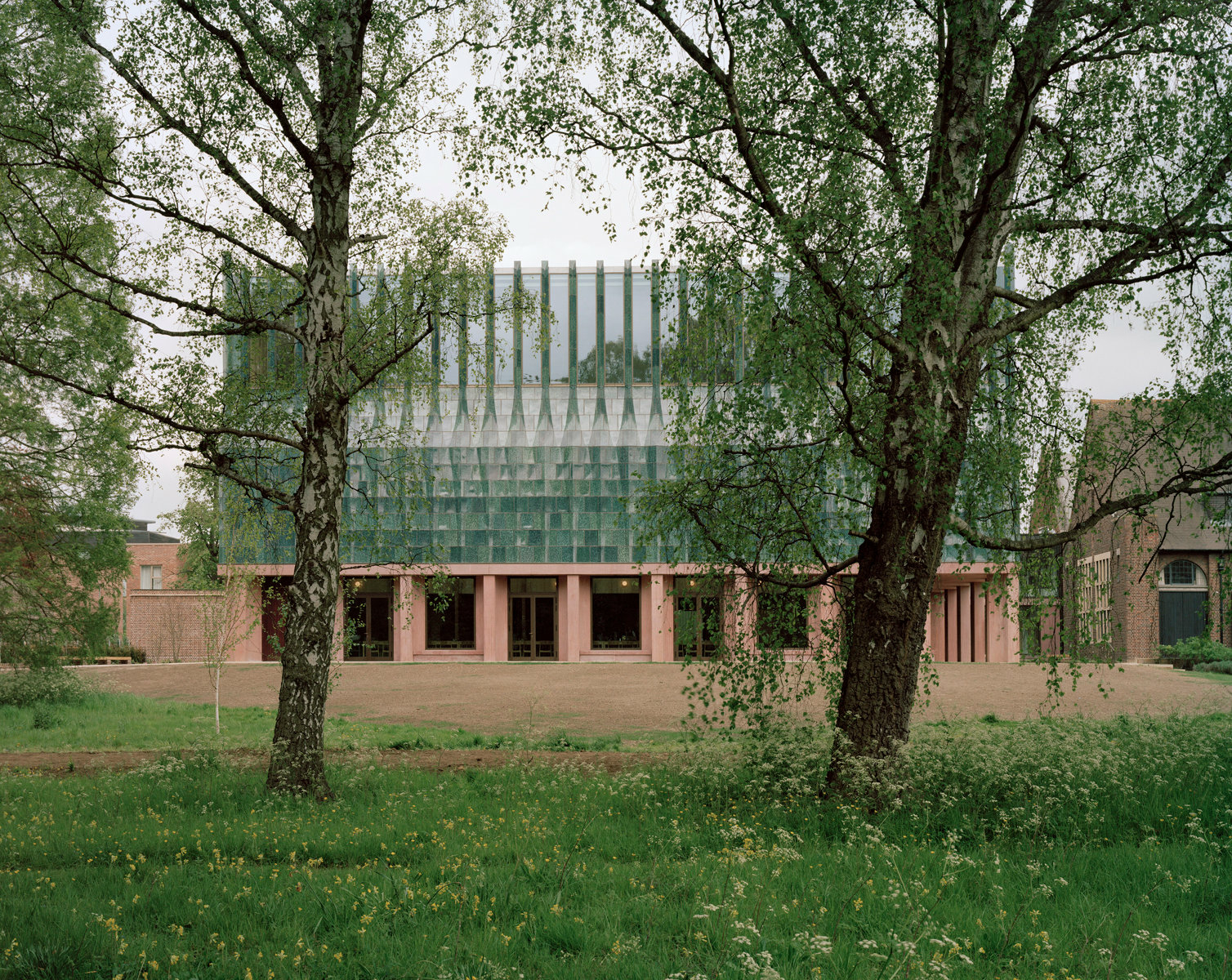 Dem Sockel des Speisesaals aus rot pigmentiertem Ortbeton setzten die Architekt*innen eine Krone mit ausdrucksstarken blaugrün schimmernden Fliesen auf. 