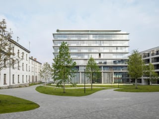 Auf dem ehemaligen Gelände der Herkenrode-Kaserne im belgischen Hasselt ist ein neungeschossiger Wohnungsbau mit gläserner Ummantelung entstanden. 