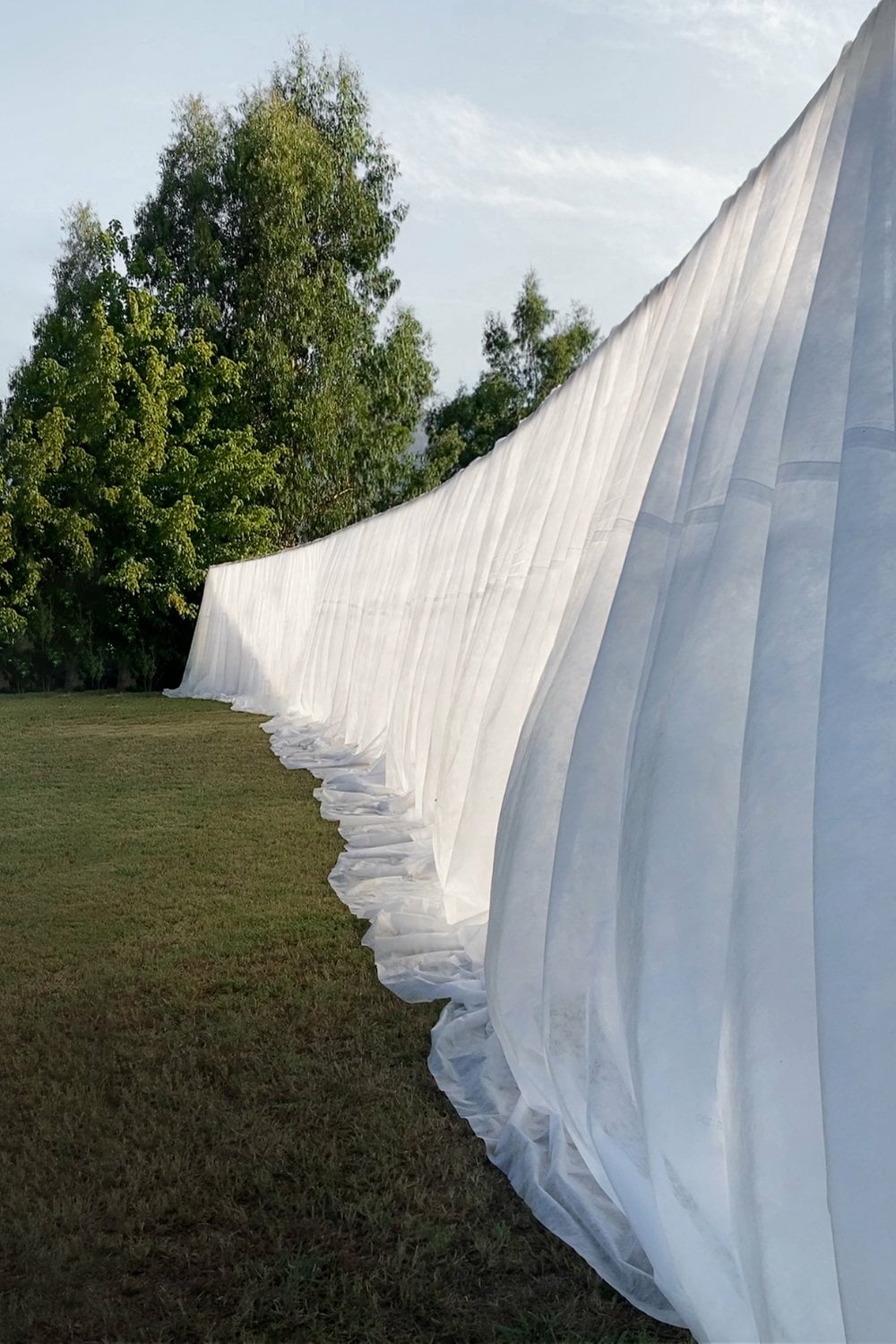 Von den Riegeln der einfachen Holzständerkontruktion hing weißes, transluzentes Textil herab.