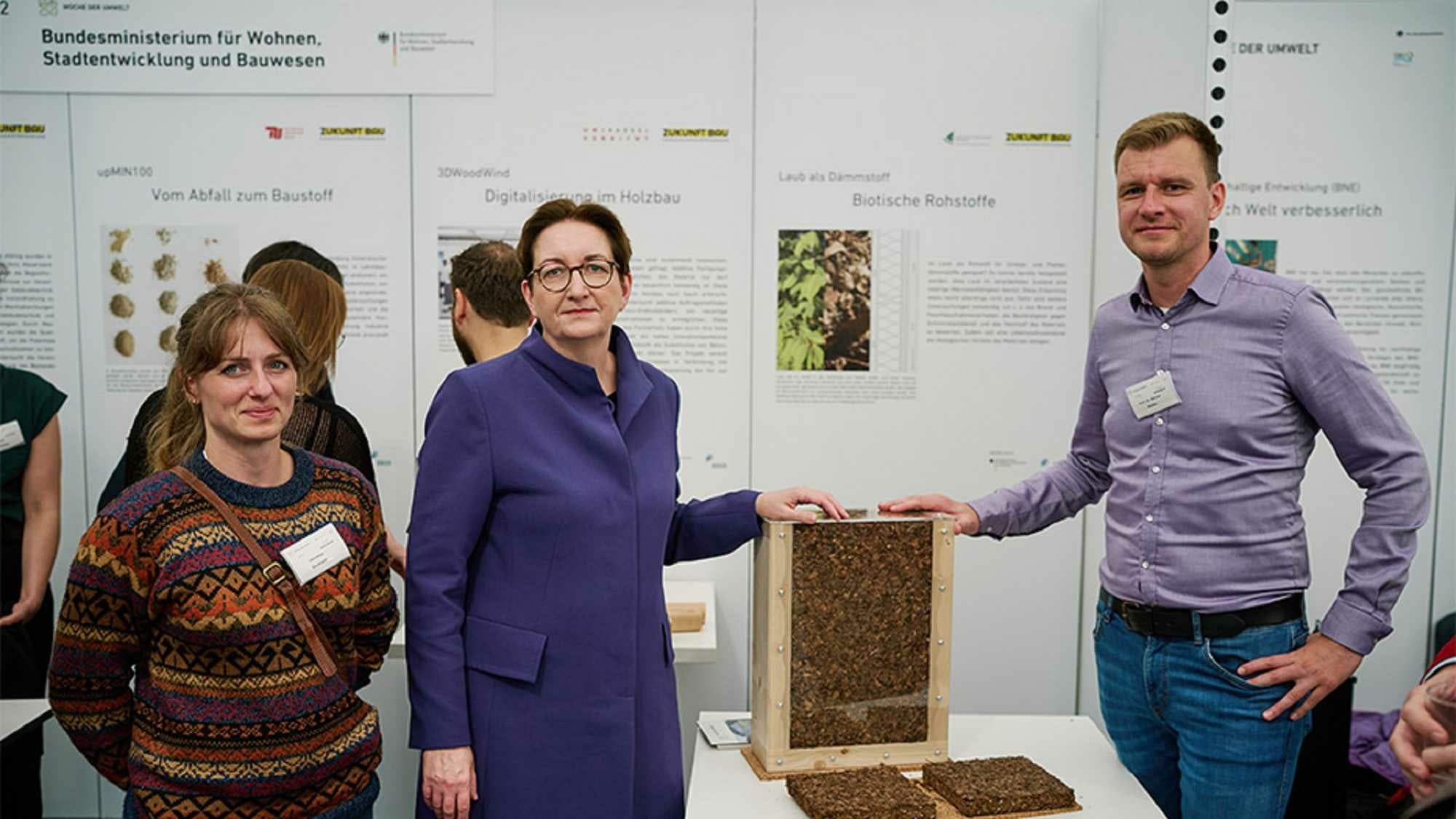 Marcus Müller (rechts) und Christina Zwanger (links) präsentieren gemeinsam mit der Bundesbauministerin Klars Geywitz einen Prototypen, der Laub als Schütt- und Einblasdämmung sowie als Dämmplatte zeigt.