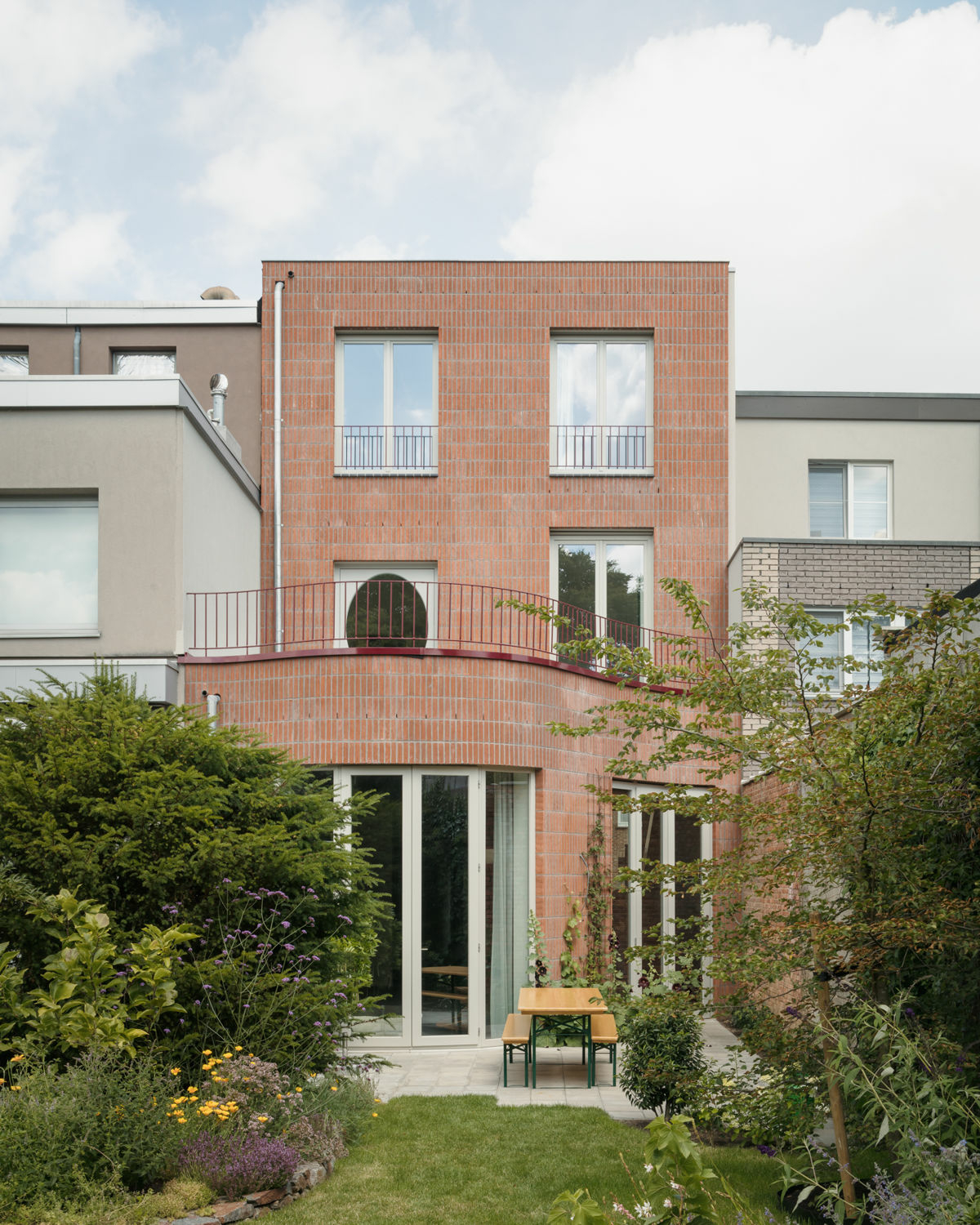 Auch gartenseitig schlägt das Haus im Erdgeschoss Wellen, während die oberen Geschosse sich an die Flucht der benachbarten Häuser anpassen.