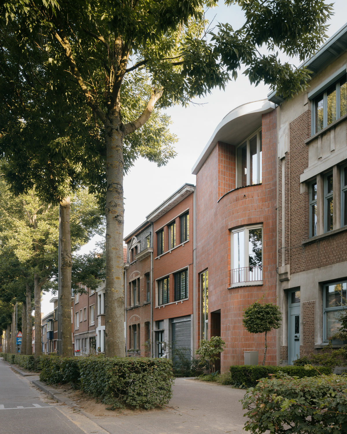 Die großen, unregelmäßigen Fassadenöffnungen und die Ziegelfassade mit dem ungewöhnlichen Verband stechen zwischen den klassisch flämischen Häusern hervor.