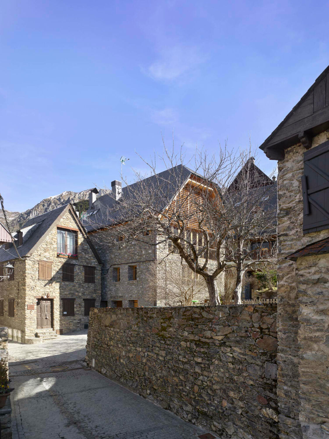 Das Wohnhaus liegt hinter einem benachbarten Wohngebäude und gegenüber von dem erhöhten, mit einer Mauer umgebenen Garten des Restaurants El Jardí Dels Pomers.