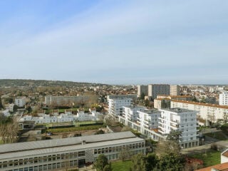 Ansicht des Geschosswohnungsbaus von Nordwesten: Auf dem langgestreckten, gemeinsamen Sockel mit gewerblicher Nutzung erheben sich vier- bis sechsgeschossige Baukörper mit Sozialwohnungen.