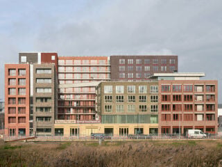 Was nach außen wie ein gewachsenes Konglomerat unterschiedlicher Häuser wirkt, ist tatsächlich ein zusammenhängender Gebäudekomplex, den das Büro Shift architecture urbanism gemeinsam mit den Kreativagenturen Synchroon und staat Amsterdam für das neue Quartier entworfen hat.