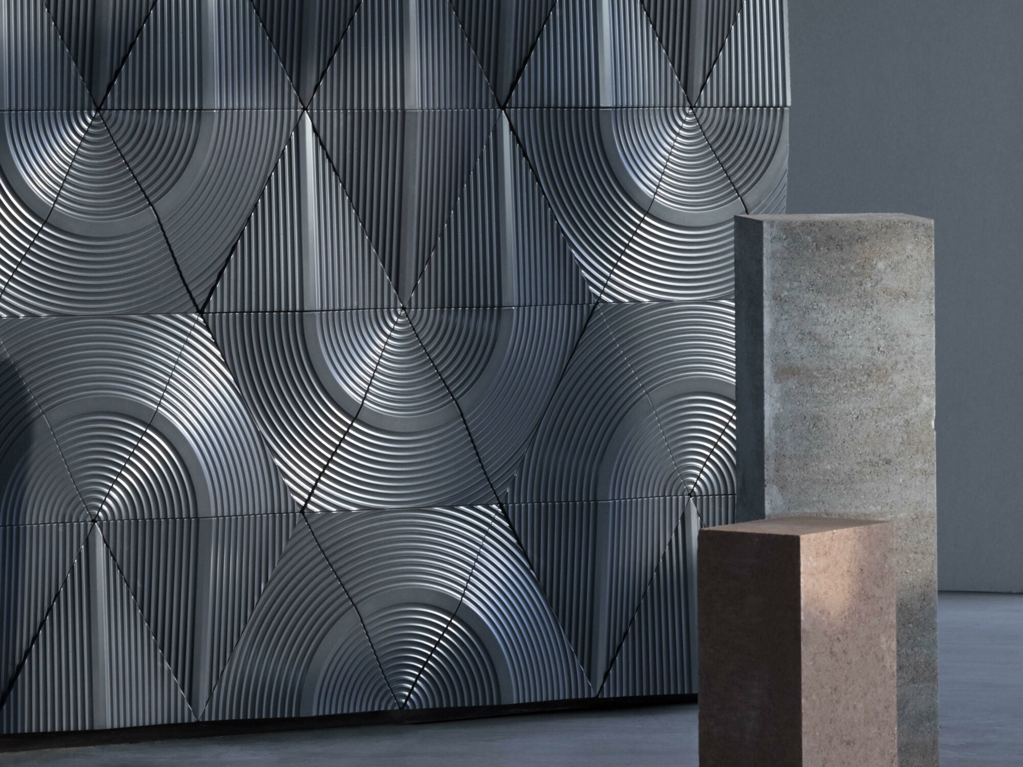Die Wandfliesen Clamo 026 weisen ein metallisches Schimmern und kreisförmige Rillen auf, die an Vinylplatten erinnern.