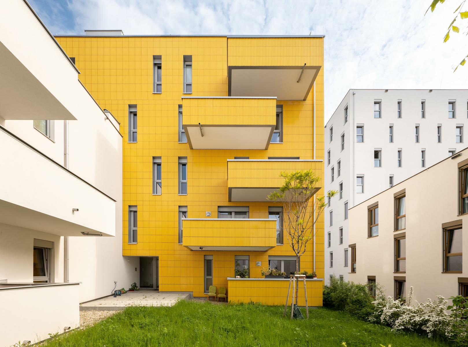 Wie Sonnenblumen, sind die Außenwände der Wohneinheiten zur Sonne ausgerichtet. Die Referenz der Sonnenblume wird durch die in gelben Tonplatten bekleideten Fassaden unterstrichen.