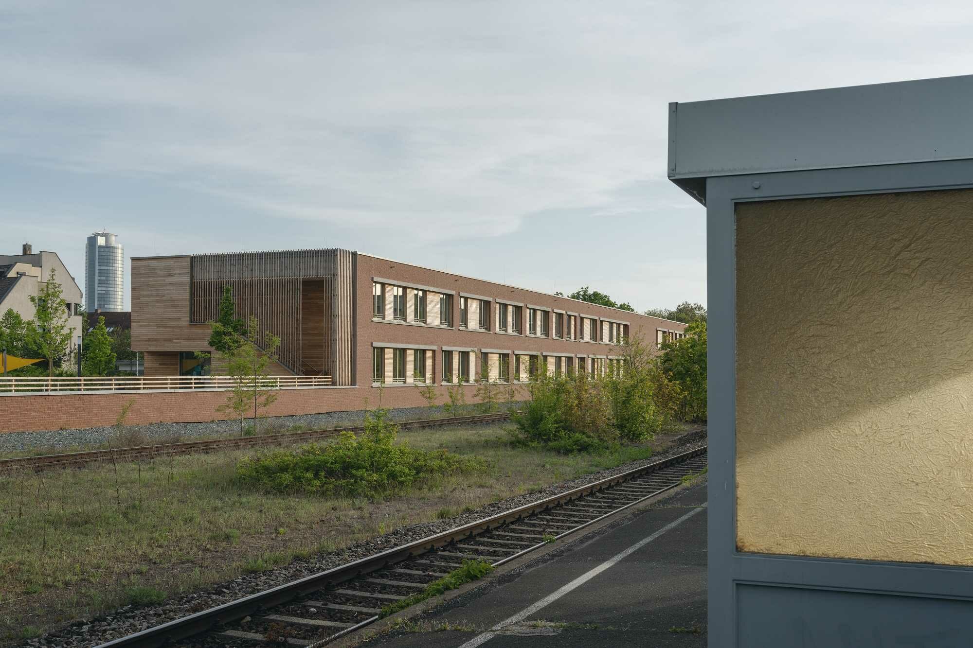 Der L-förmige Neubau schirmt den begrünten Gartenbereich von der Bahnlinie ab.