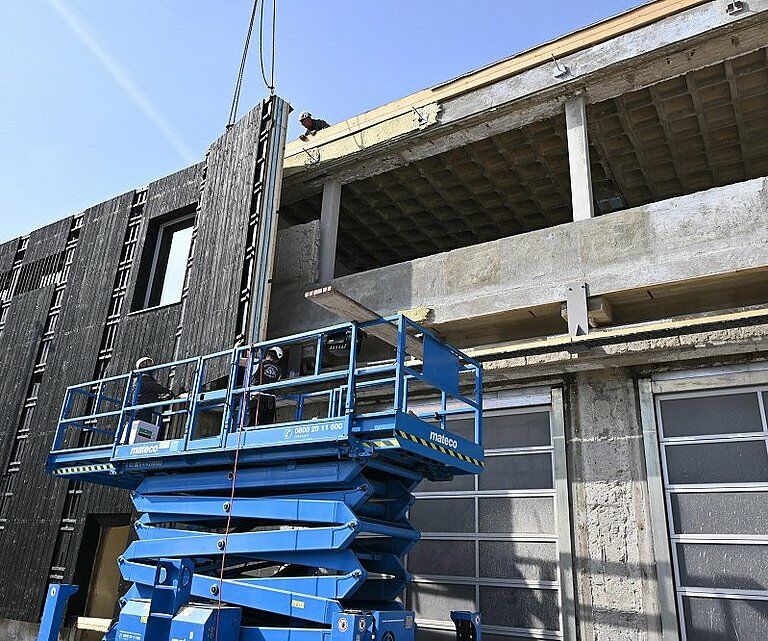 Die neue Gebäudehülle besteht aus 86 rund 8,58 Meter hohen und 2,36 Meter breiten Fassadenelementen in Holztafelbauweise.