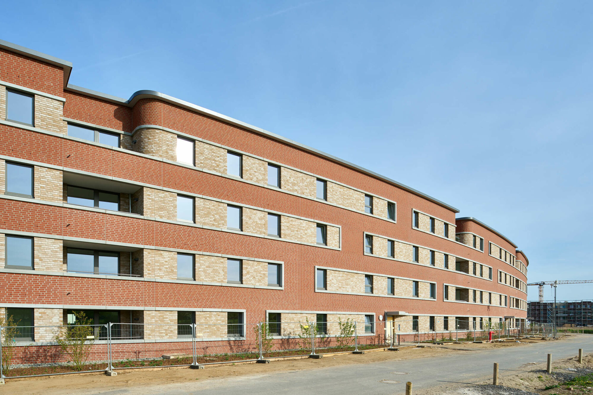 Am Bogen-Haus betonen farblich abgesetzte Mauerwerksbänder die Horizontale der langen Gebäudefigur, die an Wohnbauprojekte aus den 1920er- und 30er-Jahren im Stil der Neue Sachlichkeit erinnert.
