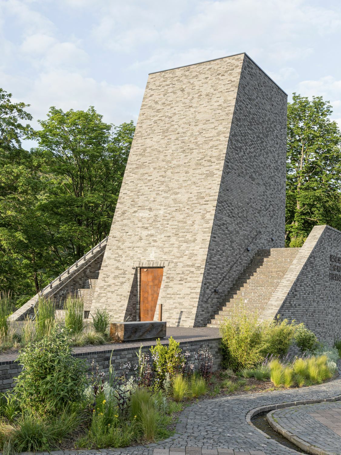 Der Baukörper wirkt archaisch und erinnert in seiner Struktur an Tempelarchitekturen: Mit einem zentralen Hochpunkt, flankiert von zwei Treppenläufen. 
