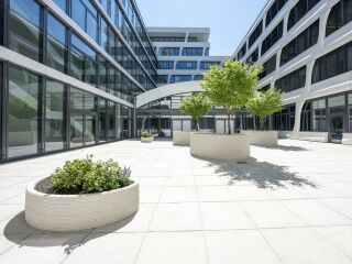Der Hersteller Heidelberg Materials wählte für seine Unternehmenszentrale eine Freiraumgestaltung, die das 3D-Betondruckverfahren mit Material aus eigenem Haus anwendet.