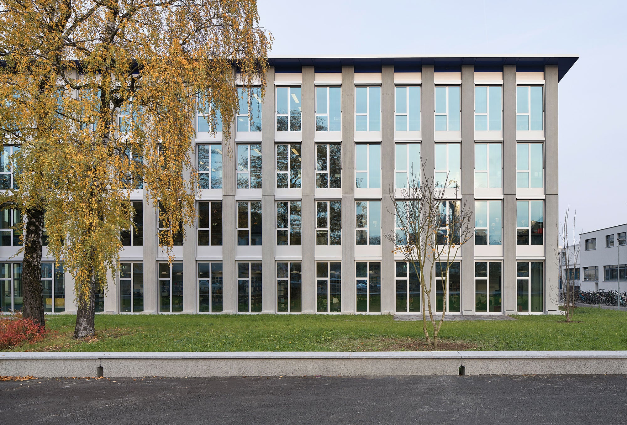 Zwischen den doppelgeschossigen, vorgefertigten Sichtbetonstützen sitzt eine Leichtbaufassade