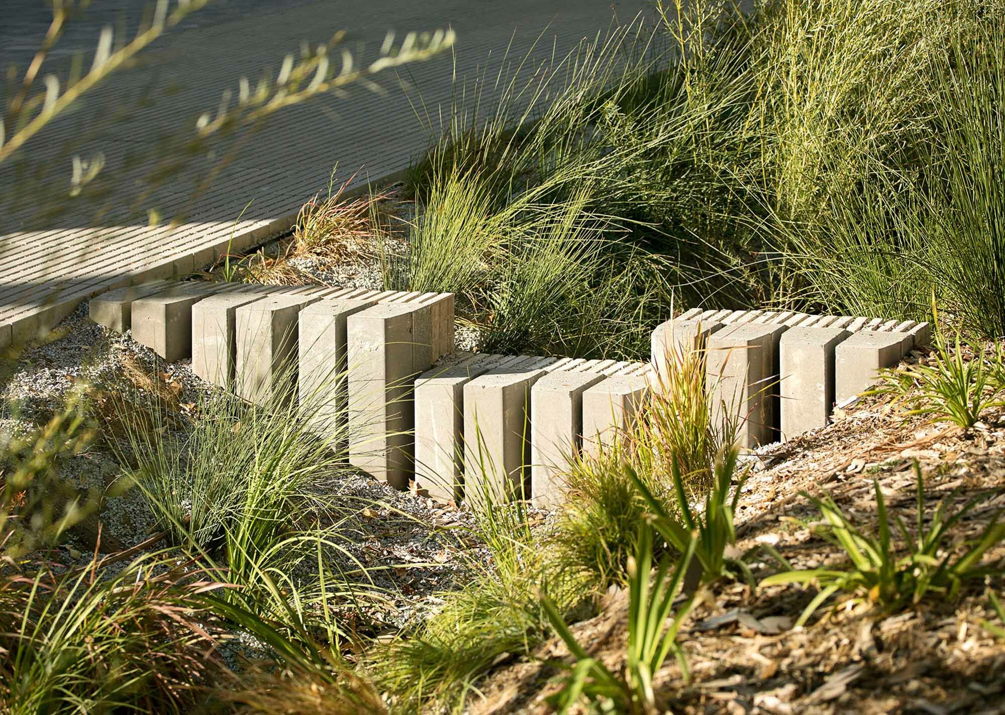 Deiche aus recycelten Elementen verlangsamen das abfließende Wasser und sorgen dafür, dass es in den linearen Rinnen versickert.