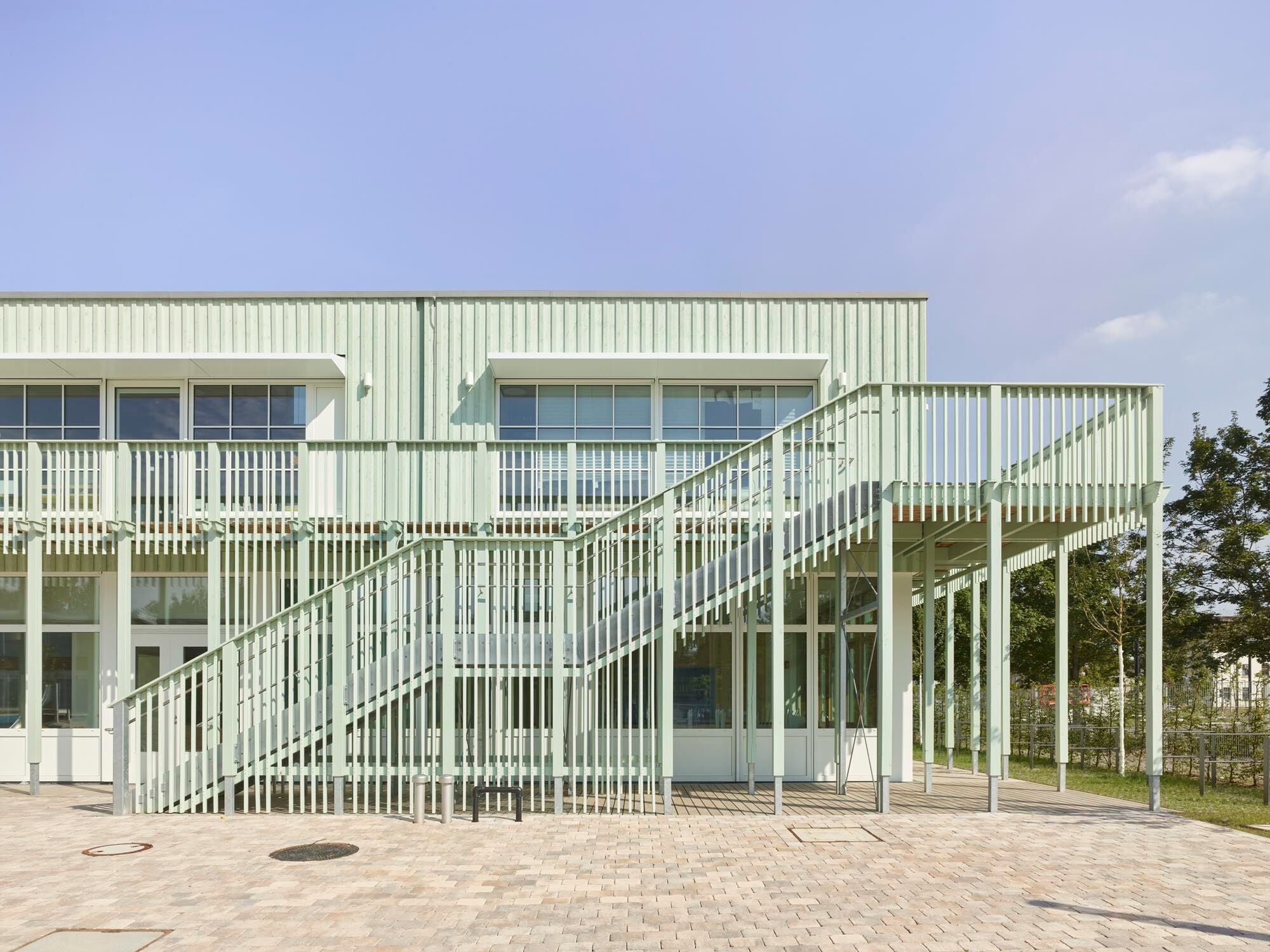 Am Schulgebäude dienen umlaufende Balkone als Fluchtweg, konstruktiver Holzschutz und Sonnenschutz.