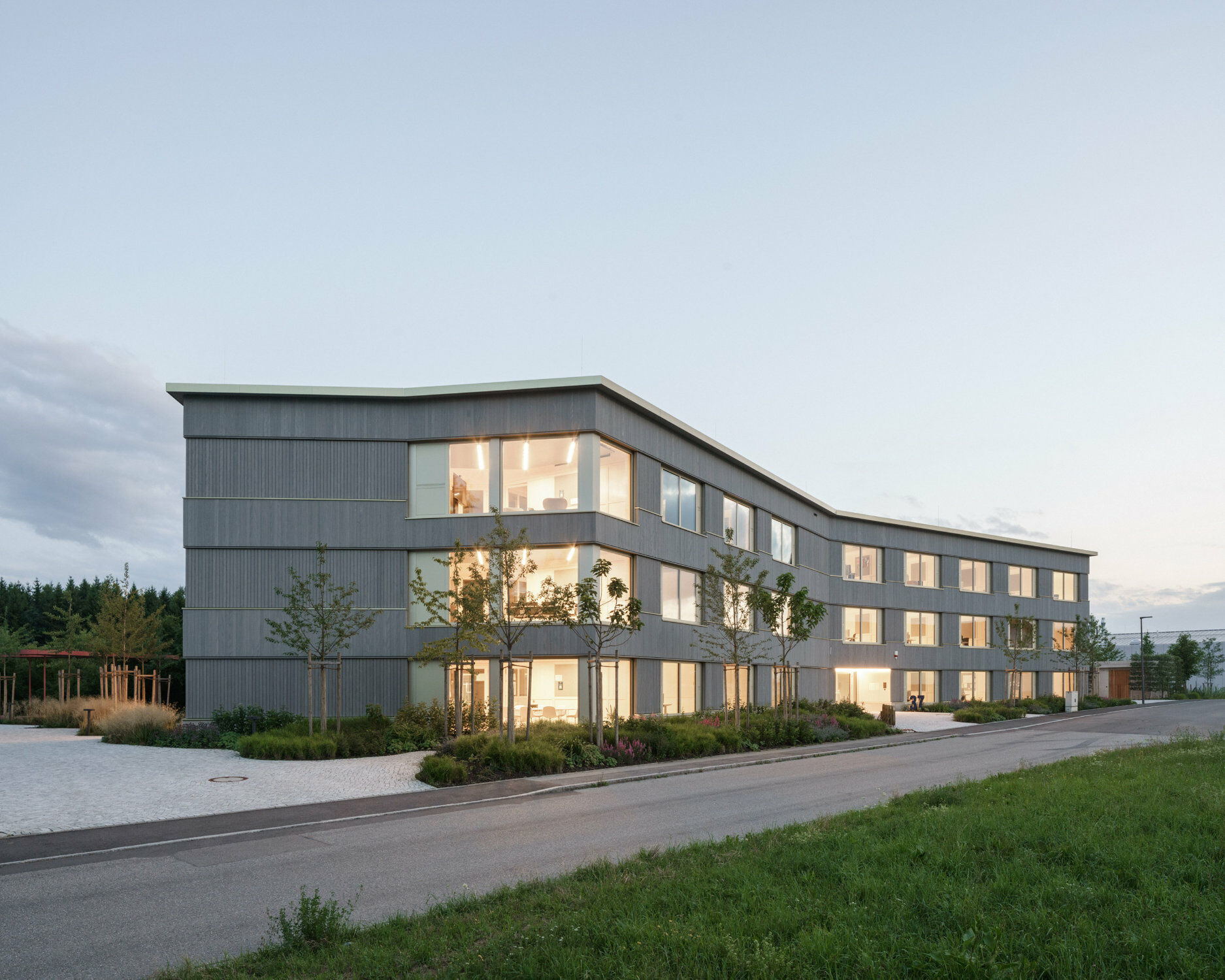 Eine Holzschalung aus vorvergrauter Weißtanne und leicht golden eloxierte Holz-Alufenster prägen die Fassade.