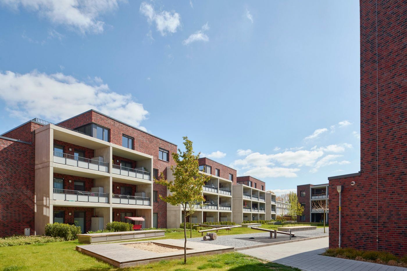 Während beide Wohnungsbauten sich zum gemeinsamen Innenhof und zueinander öffnen, schafft der dritte Teil des Ensembles einen eigenen Vorplatz.
