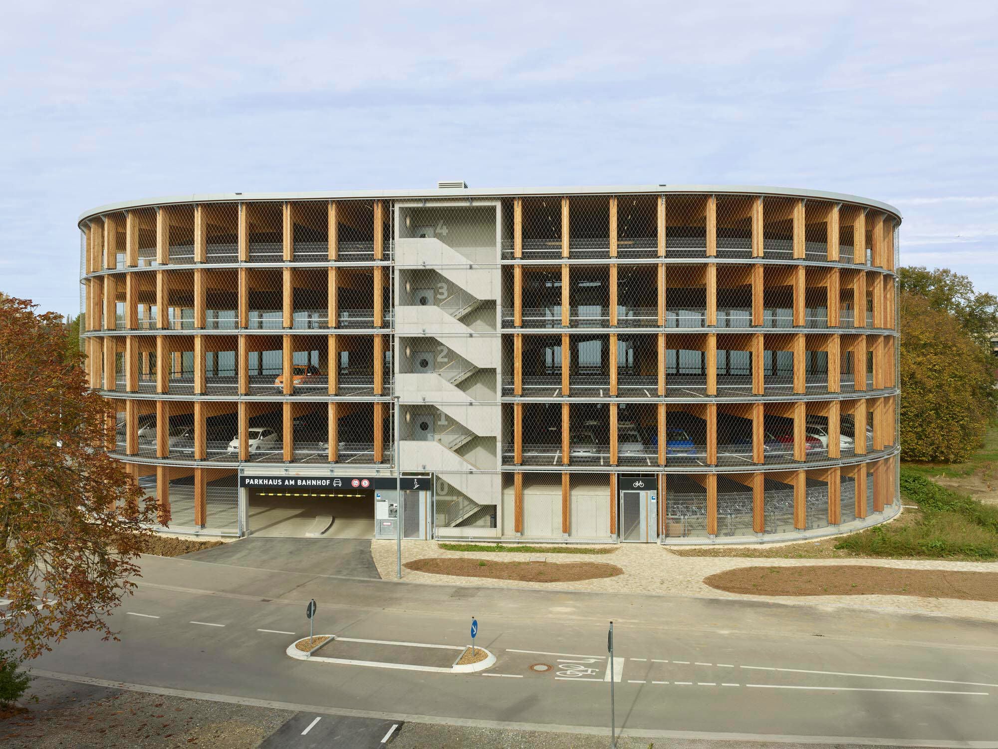 Außenansicht der offenen Holzkonstruktion mit einem der zwei Treppenhäuser aus Stahlbeton
