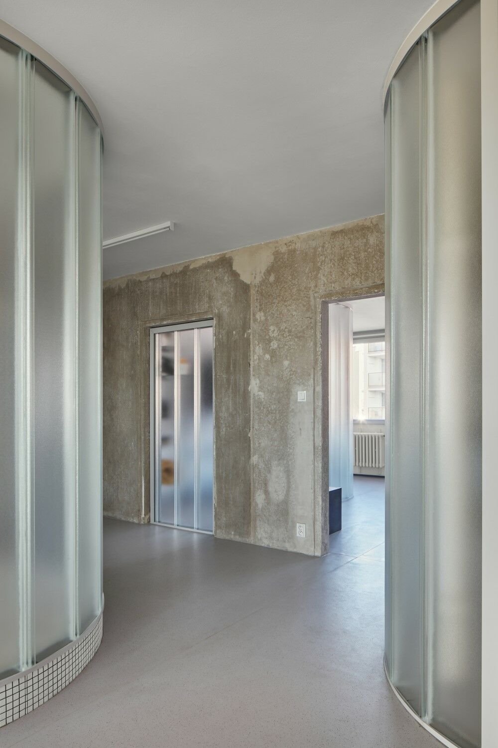 Eine tragende Sichtbetonwand aus dem Bestand wurde erhalten und unterteilt die Wohnung in zwei größere Bereiche. 